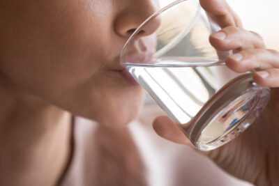 una imagen de una mujer bebiendo agua y sosteniendo un vaso en su mano
