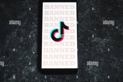 una mano sosteniendo un telefono movil con el icono de facebook rodeado por un circulo tachado