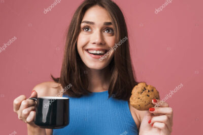 una mujer embarazada sosteniendo una taza de te de jengibre y sonriendo